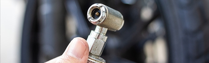 hand with a tire pressure gauge in front of a tire