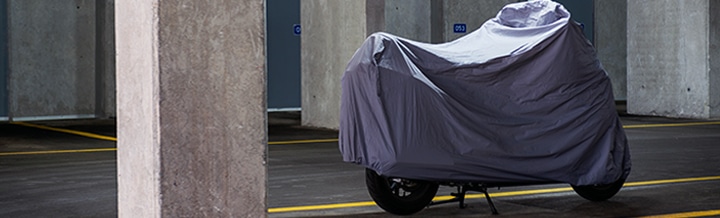 motorcycle in a garage lot with cover on it