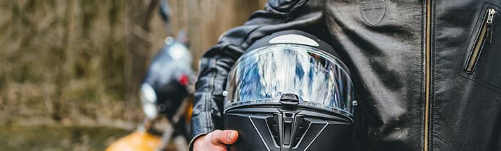 motorcycle rider holding a helmet under his arm