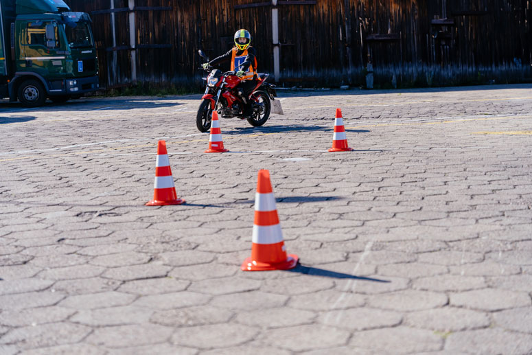 Photo of a person on a motorcycle driving around some traffic cones