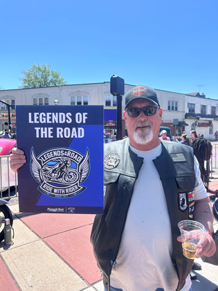 Photo of a white man holding a "legends of the road" sign