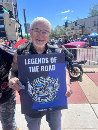 Photo of a man holding a "legends of the road" sign