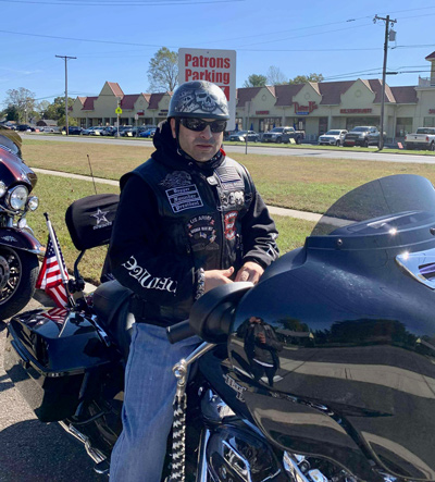 Photo of a man sitting on a motorcycle wearing sunglasses and a helmet