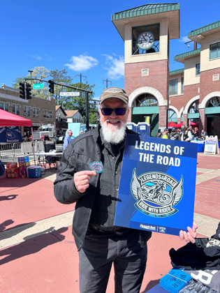 Photo of a man holding a "legends of the road" sign