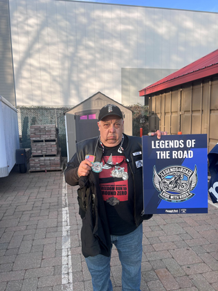 Photo of a man holding a "legends of the road" sign