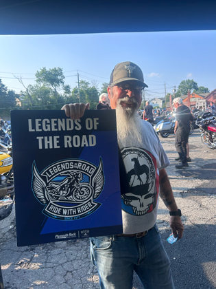 Photo of a man holding a "legends of the road" sign