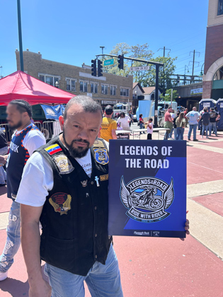 Photo of a man holding a "legends of the road" sign