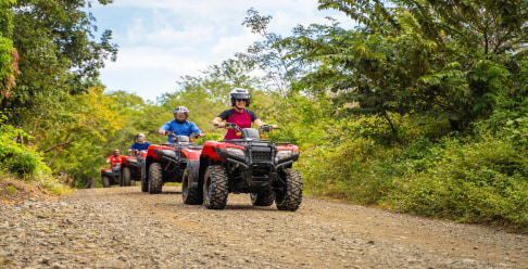 Photo of several people in a line riding ATVs outside