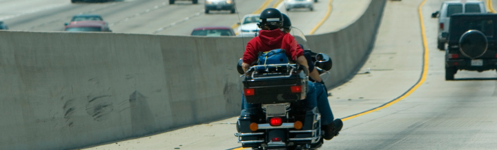 Photo of two people riding on one motorcycle down the highway