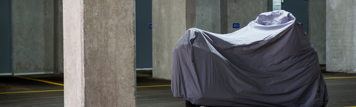 Photo of a motorcycle parked in a garage covered by a tarp