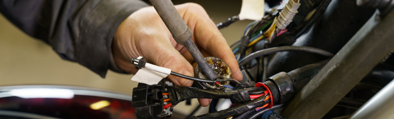 Photo of a hand working on an electrical element in a motorcycle