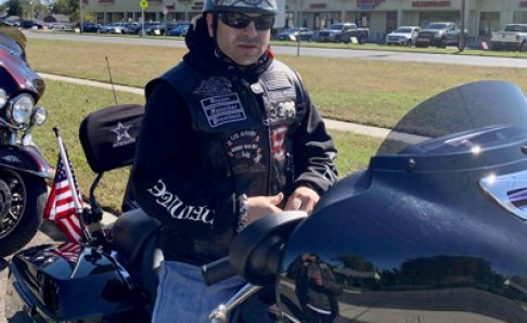 Photo of a man sitting on a motorcycle wearing sunglasses and a helmet
