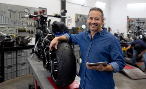 Photo of a mechanic leaning on a motorcycle