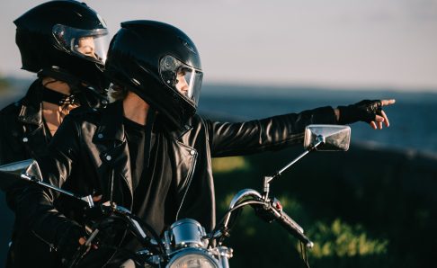 Photo of two people with helmets on riding a motorcycle